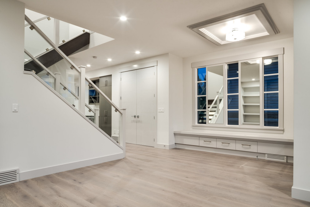 Example of a mid-sized minimalist light wood floor foyer design in Calgary with white walls and a white front door