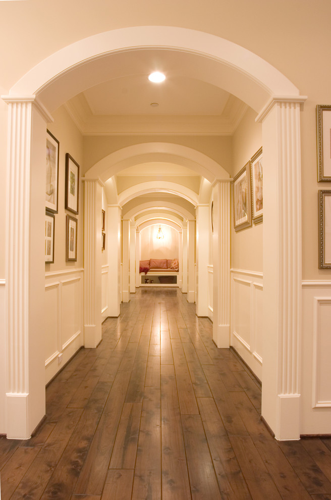 This is an example of a mid-sized traditional hallway in Houston with beige walls, dark hardwood floors and brown floor.