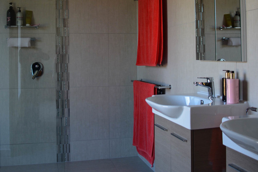 Photo of a modern bathroom in Other with an open shower, a two-piece toilet, beige tile, porcelain tile, beige walls, concrete floors, a wall-mount sink, solid surface benchtops, beige floor and an open shower.