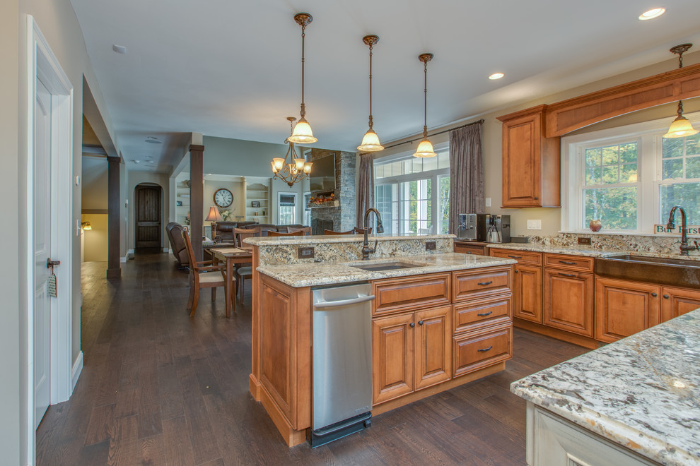 Inspiration for a large traditional u-shaped open plan kitchen in Boston with a farmhouse sink, raised-panel cabinets, medium wood cabinets, granite benchtops, stainless steel appliances, multiple islands and brown floor.