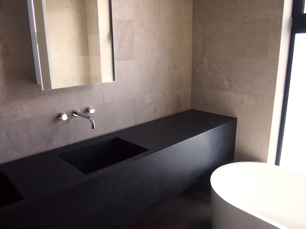 Inspiration for a contemporary bathroom in Melbourne with beige tile, an integrated sink, solid surface benchtops, black benchtops and a double vanity.