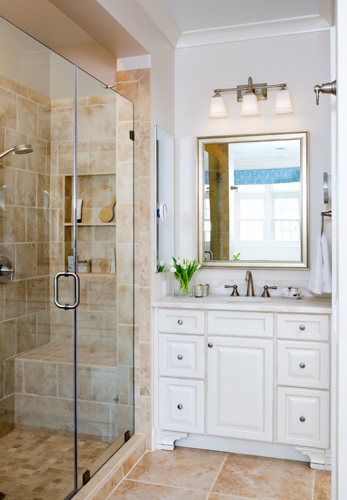 Photo of a large traditional master bathroom in DC Metro with raised-panel cabinets, white cabinets, beige tile, porcelain tile, an undermount sink, quartzite benchtops, an alcove shower, a drop-in tub, a two-piece toilet, white walls, porcelain floors, a niche and a shower seat.