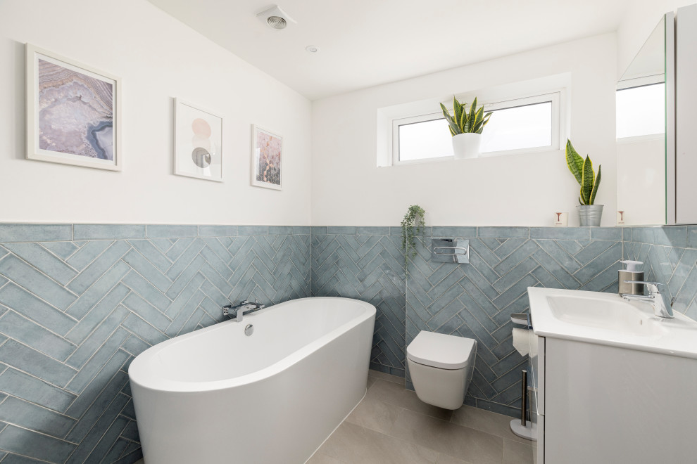 Immagine di una grande stanza da bagno per bambini tradizionale con ante lisce, ante bianche, vasca freestanding, WC sospeso, piastrelle blu, piastrelle in ceramica, pareti bianche, top in quarzite, top bianco, un lavabo, mobile bagno sospeso, doccia alcova, pavimento in gres porcellanato, lavabo integrato, pavimento grigio e porta doccia scorrevole
