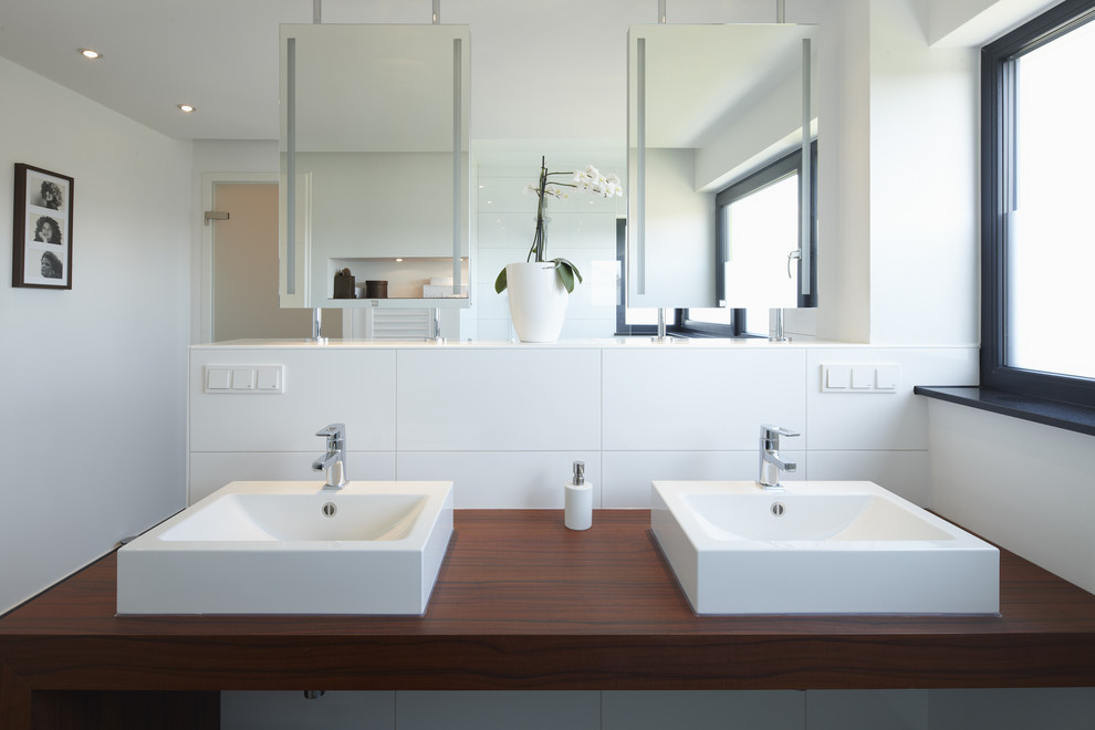 This is an example of a large contemporary bathroom in Essen with white tile, ceramic tile, white walls, a vessel sink and wood benchtops.