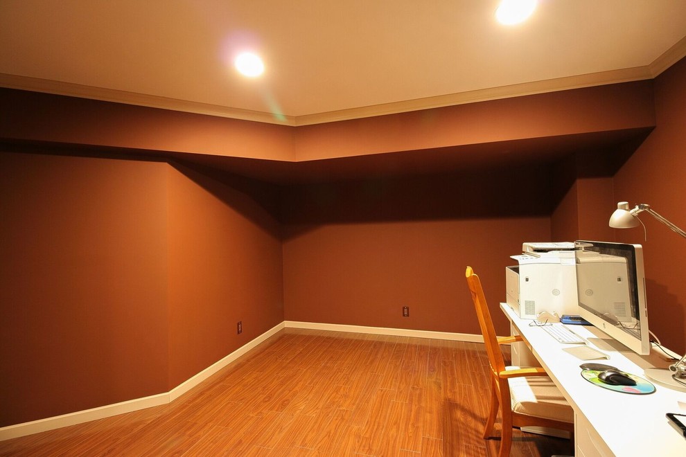 Inspiration for a mid-sized transitional underground medium tone wood floor and brown floor basement remodel in Vancouver with orange walls, a standard fireplace and a stone fireplace