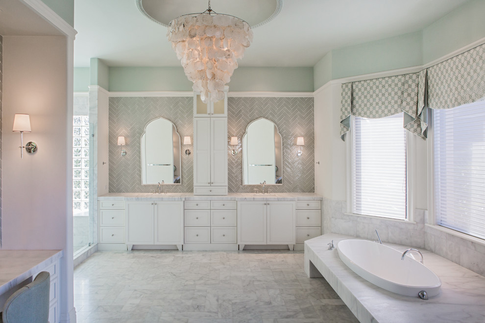 Inspiration for a transitional bathroom in Miami with recessed-panel cabinets, white cabinets, a drop-in tub, gray tile and green walls.