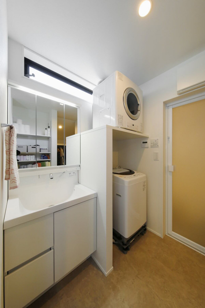 This is an example of a mid-sized modern single-wall utility room in Tokyo Suburbs with an integrated sink, white cabinets, white walls, concrete floors, a stacked washer and dryer, grey floor, wallpaper, wallpaper, concrete benchtops and white benchtop.