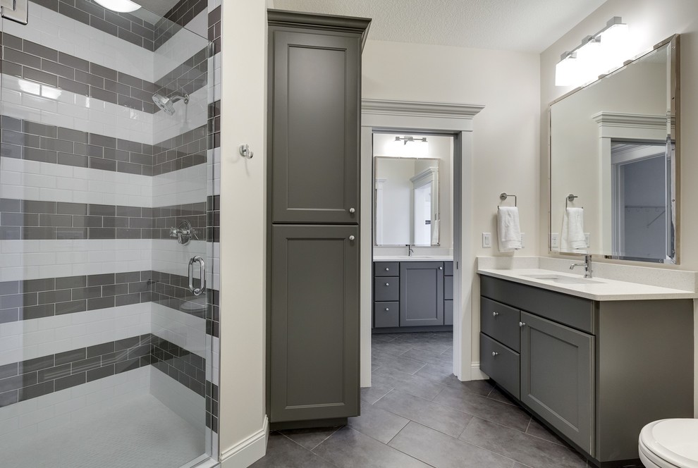 This is an example of a traditional kids bathroom in Minneapolis with recessed-panel cabinets, grey cabinets, an alcove shower, beige walls, an undermount sink, granite benchtops, grey floor and a hinged shower door.