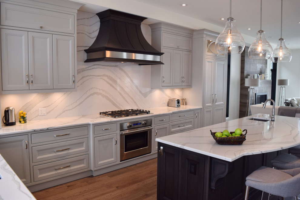 Open concept kitchen - large l-shaped medium tone wood floor and brown floor open concept kitchen idea in Ottawa with an undermount sink, recessed-panel cabinets, white cabinets, quartz countertops, white backsplash, quartz backsplash, paneled appliances, an island and white countertops