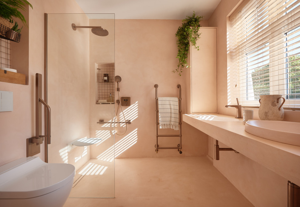 Photo of a mid-sized modern master bathroom in London with open cabinets, an open shower, a wall-mount toilet, pink tile, cement tile, pink walls, concrete floors, an integrated sink, concrete benchtops, pink floor, an open shower and pink benchtops.