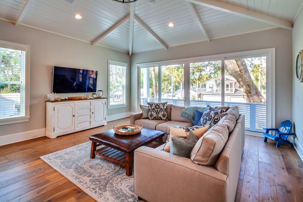 Inspiration for a mid-sized beach style open concept family room in Jacksonville with grey walls, medium hardwood floors, no fireplace and a wall-mounted tv.