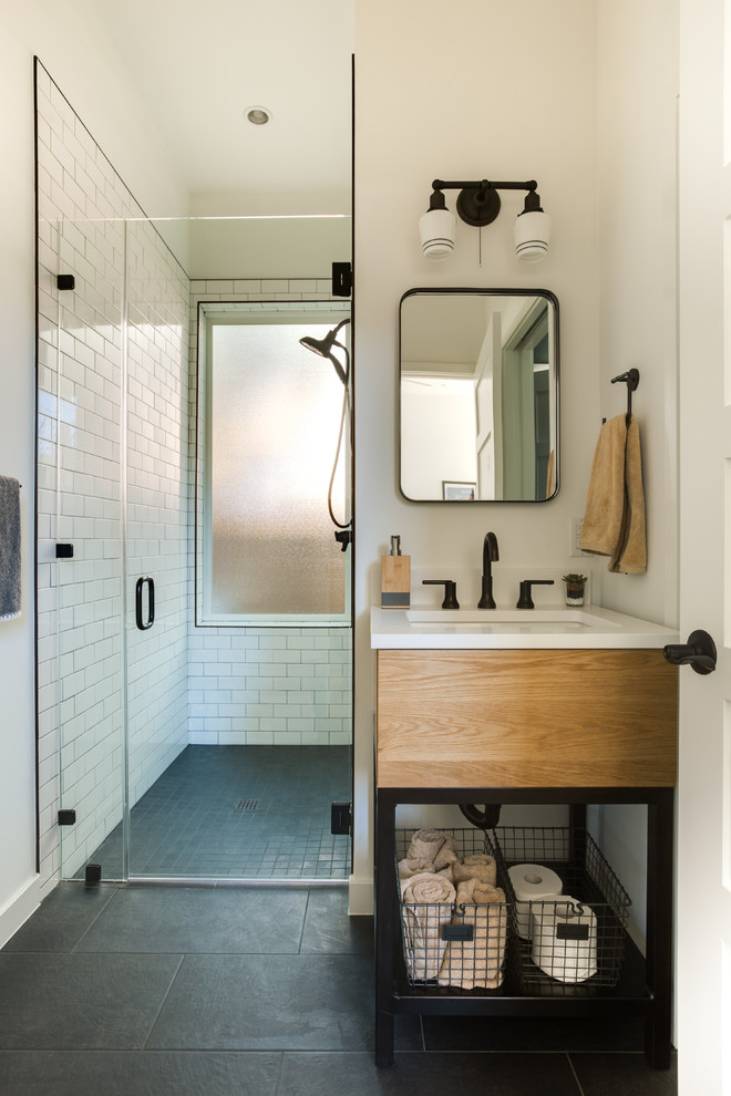 Inspiration for a transitional 3/4 bathroom in Austin with flat-panel cabinets, medium wood cabinets, a curbless shower, white tile, subway tile, white walls, an undermount sink, grey floor and a hinged shower door.