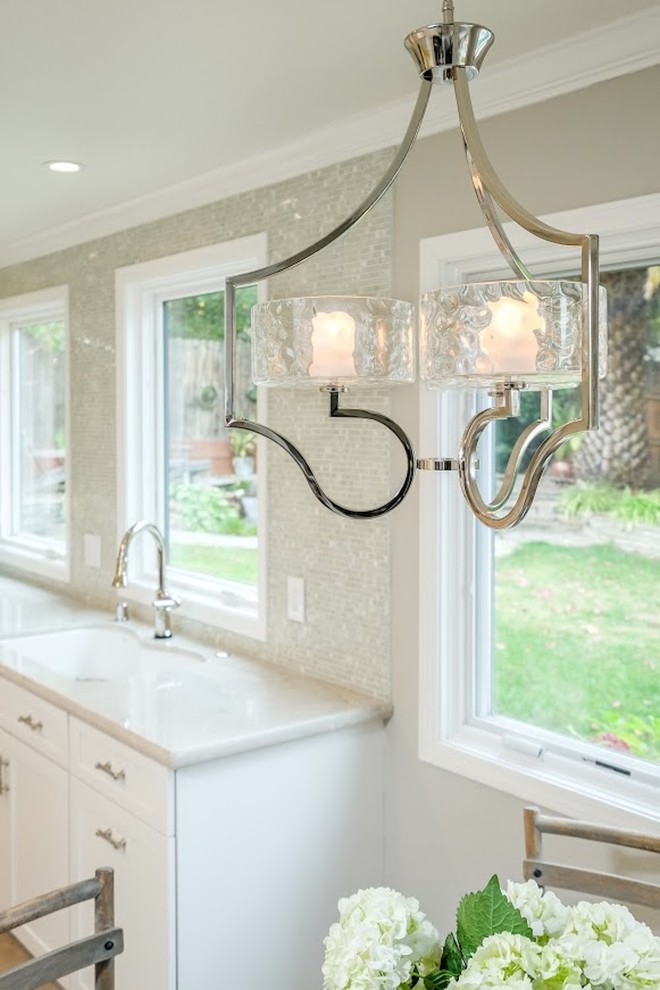 Inspiration for a large transitional u-shaped limestone floor eat-in kitchen remodel with an undermount sink, shaker cabinets, white cabinets, marble countertops, metallic backsplash, mosaic tile backsplash, stainless steel appliances and an island