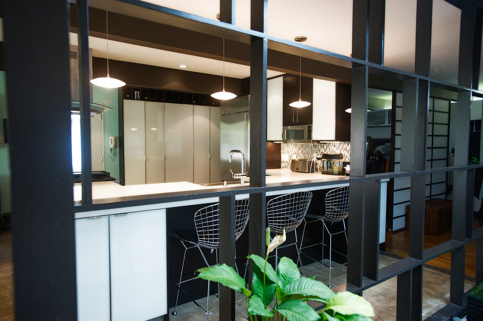 Photo of a midcentury u-shaped open plan kitchen in Houston with a single-bowl sink, flat-panel cabinets, black cabinets, quartz benchtops, grey splashback, matchstick tile splashback and stainless steel appliances.