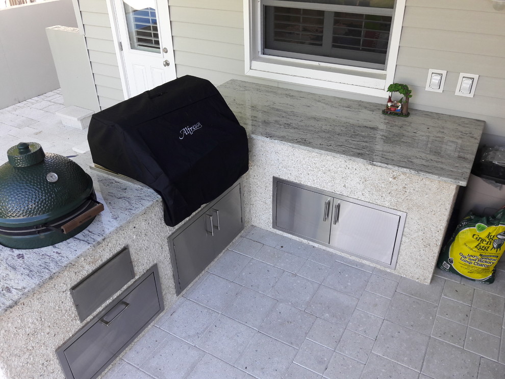 Large backyard deck in Tampa with an outdoor kitchen and a roof extension.