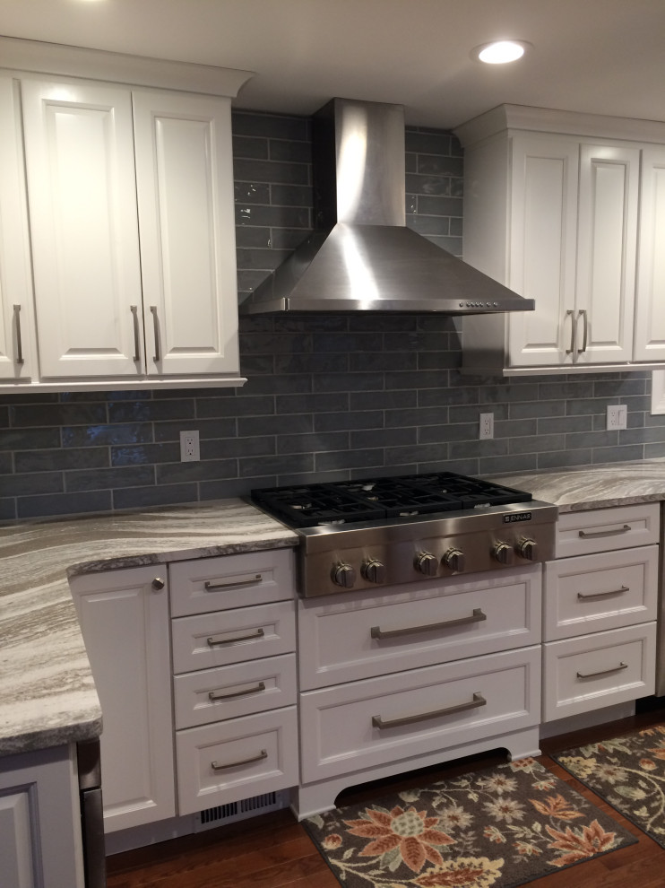 Eat-in kitchen - mid-sized transitional u-shaped medium tone wood floor and brown floor eat-in kitchen idea with an undermount sink, raised-panel cabinets, white cabinets, granite countertops, blue backsplash, ceramic backsplash, stainless steel appliances, a peninsula and gray countertops