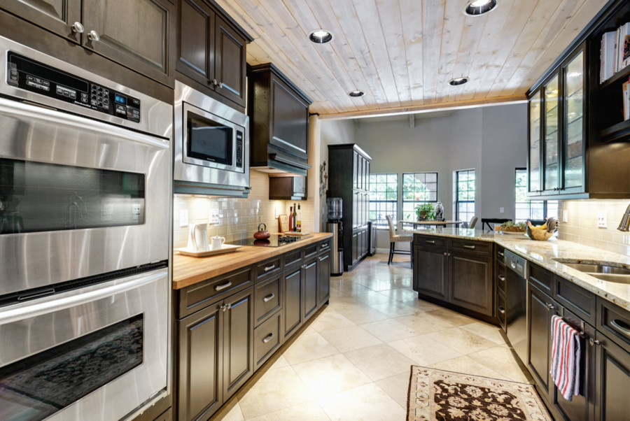 Small trendy galley travertine floor enclosed kitchen photo in Phoenix with an undermount sink, raised-panel cabinets, gray cabinets, granite countertops, beige backsplash, subway tile backsplash, stainless steel appliances and a peninsula