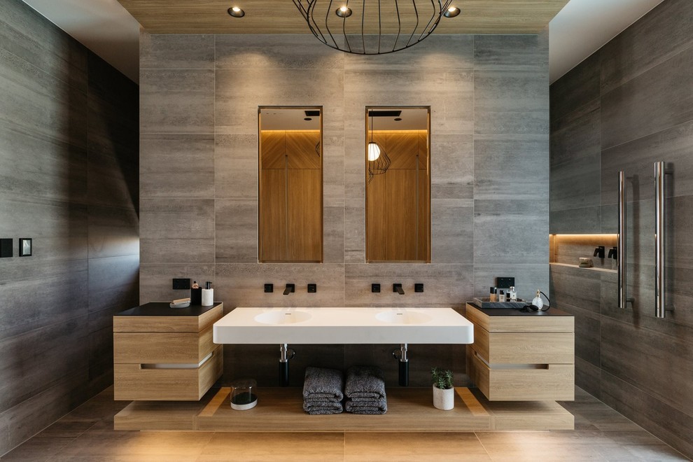 Inspiration for a large contemporary master bathroom in Adelaide with light wood cabinets, gray tile, grey walls, flat-panel cabinets, an open shower, a wall-mount sink, an open shower, porcelain tile, porcelain floors, engineered quartz benchtops, grey floor and brown benchtops.