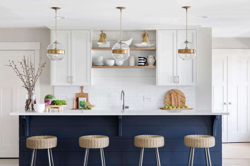 Inspiration for a transitional galley open plan kitchen in Minneapolis with shaker cabinets, white cabinets, quartz benchtops, white splashback, stainless steel appliances, white benchtop, an undermount sink, subway tile splashback, ceramic floors and with island.
