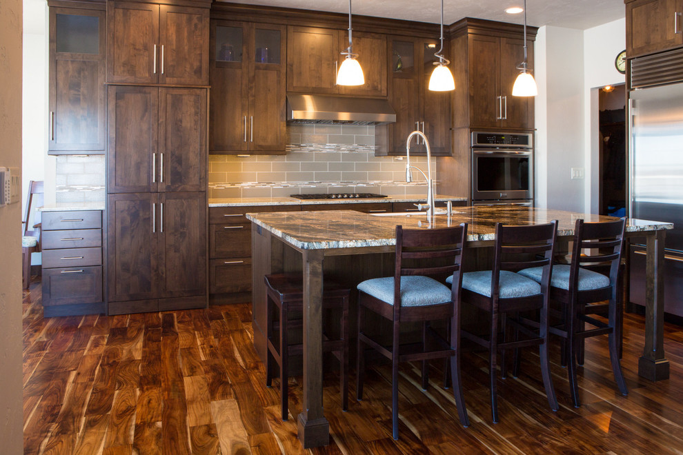 Open concept kitchen - large transitional l-shaped dark wood floor and brown floor open concept kitchen idea with a farmhouse sink, shaker cabinets, dark wood cabinets, granite countertops, beige backsplash, subway tile backsplash, stainless steel appliances and an island