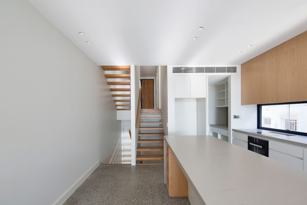 This is an example of a mid-sized contemporary galley kitchen pantry in Sydney with flat-panel cabinets, quartz benchtops, concrete floors, with island and beige benchtop.