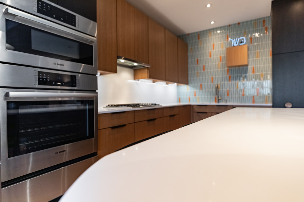 Medium sized contemporary l-shaped open plan kitchen in Philadelphia with a submerged sink, flat-panel cabinets, brown cabinets, engineered stone countertops, white splashback, porcelain splashback, stainless steel appliances, light hardwood flooring, an island, brown floors and white worktops.