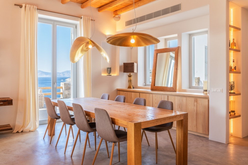 This is an example of a beach style dining room in Other with white walls and grey floor.