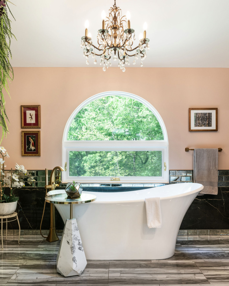 Cette image montre une salle de bain traditionnelle avec une baignoire indépendante, un carrelage noir, un mur beige et un sol gris.