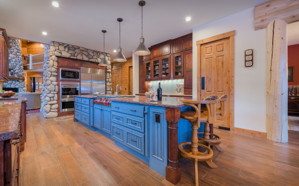 This is an example of a country l-shaped kitchen in Denver with recessed-panel cabinets, dark wood cabinets, stainless steel appliances, medium hardwood floors and with island.