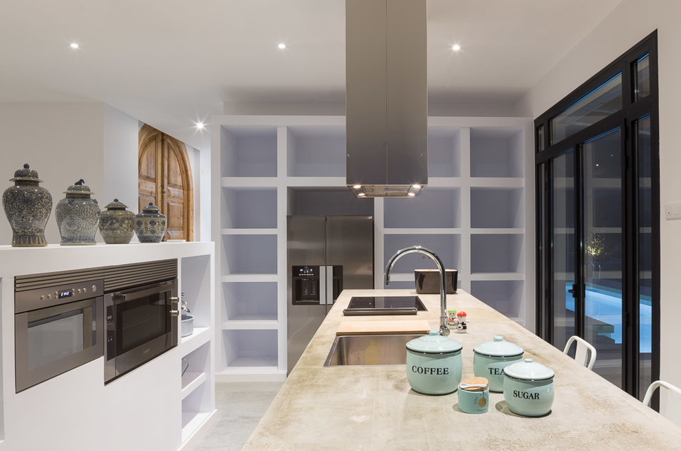 Design ideas for a mid-sized transitional galley eat-in kitchen in Barcelona with an integrated sink, open cabinets, white cabinets, concrete benchtops, white splashback, stainless steel appliances, concrete floors and with island.