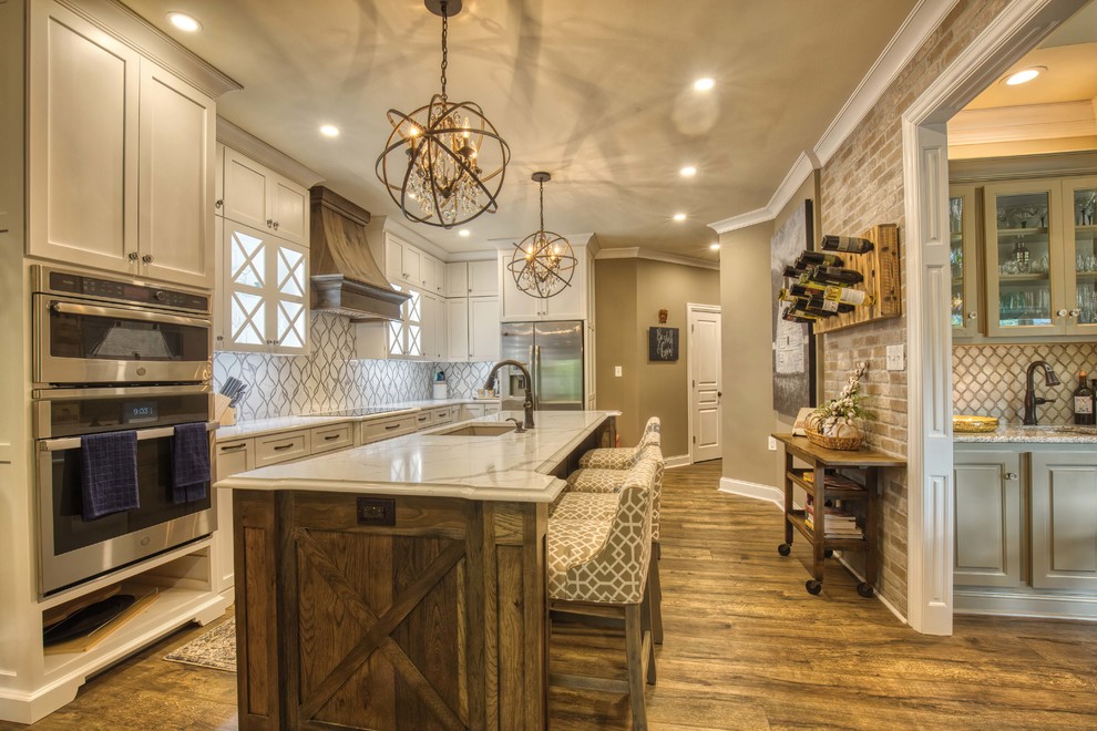 Design ideas for a large country eat-in kitchen in Louisville with a farmhouse sink, white cabinets, granite benchtops, white splashback, stainless steel appliances, vinyl floors, with island, brown floor and white benchtop.