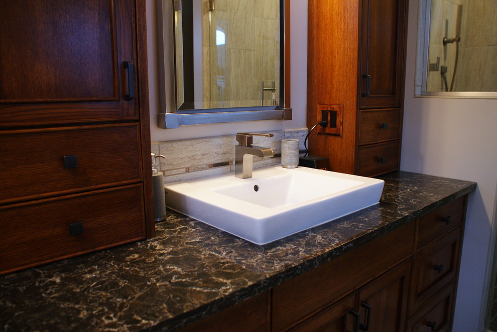 Example of a mid-sized transitional master gray tile and porcelain tile porcelain tile drop-in bathtub design in Minneapolis with a vessel sink, beaded inset cabinets, dark wood cabinets, quartzite countertops, a one-piece toilet and gray walls