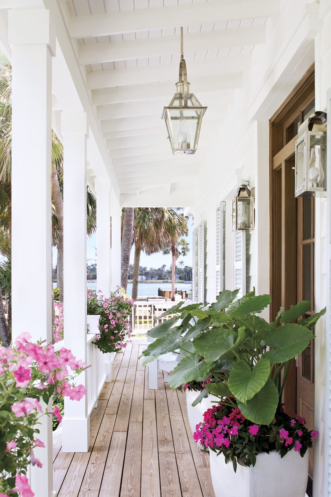 Mid-sized beach style front yard verandah in New Orleans with a container garden, natural stone pavers and a roof extension.