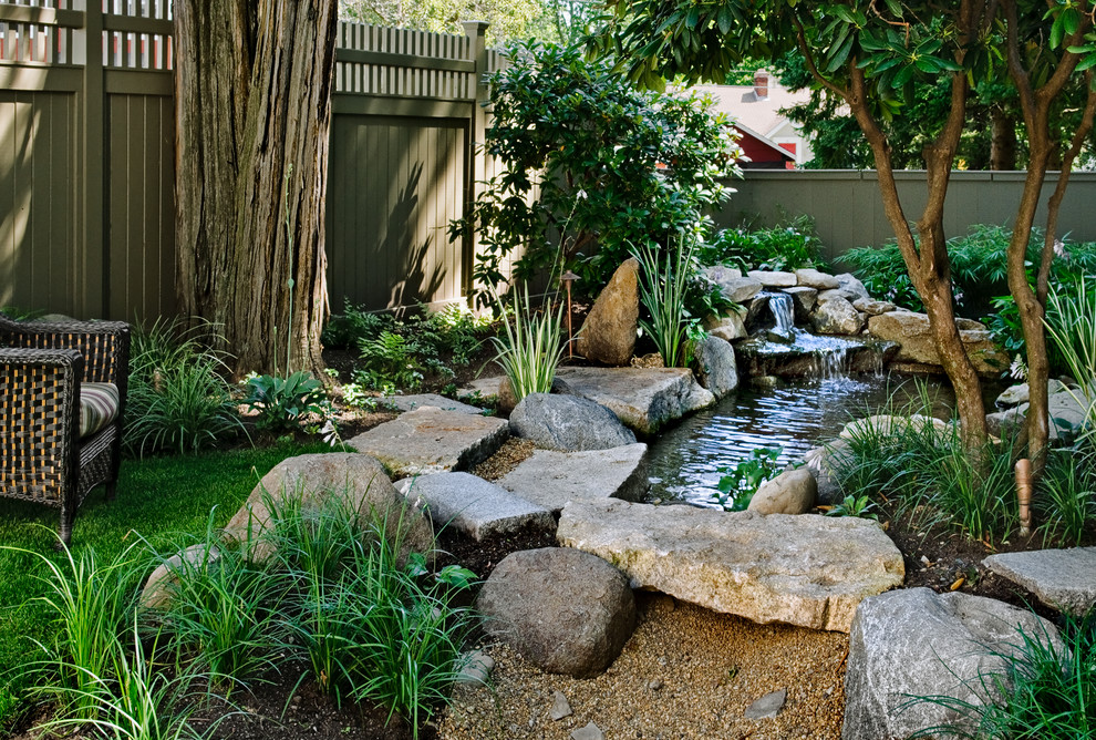 Small traditional backyard shaded garden in Portland Maine with a water feature and natural stone pavers for summer.