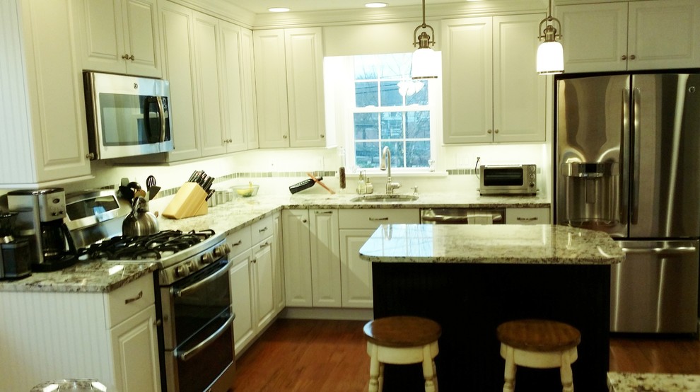 Mid-sized traditional l-shaped eat-in kitchen in Baltimore with raised-panel cabinets, white cabinets, granite benchtops, white splashback, stainless steel appliances, light hardwood floors, with island, an undermount sink and stone tile splashback.