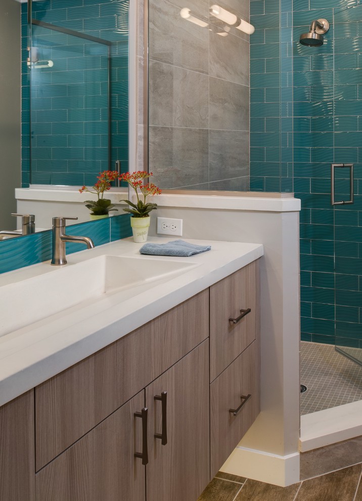 Inspiration for a mid-sized midcentury bathroom with flat-panel cabinets, medium wood cabinets, a corner shower, blue tile, glass tile, grey walls, porcelain floors, a trough sink and concrete benchtops.