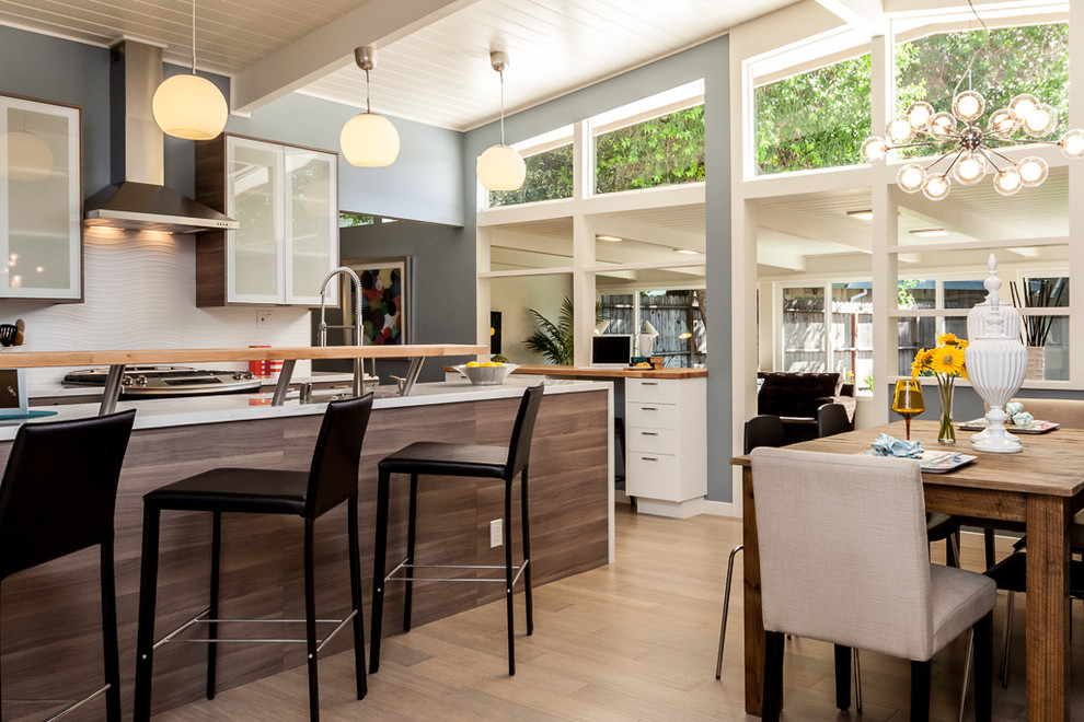 Cette image montre une petite salle à manger ouverte sur la cuisine vintage avec un mur bleu, parquet en bambou et aucune cheminée.