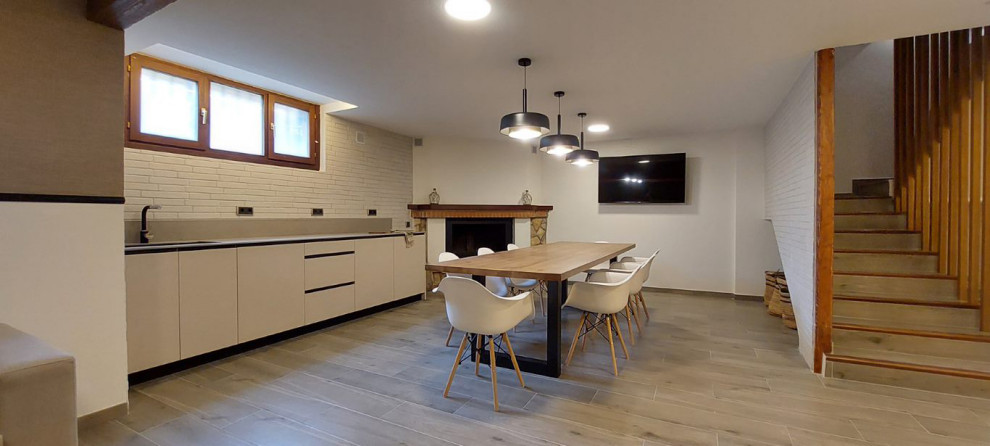 Imagen de sótano con cocina actual grande con suelo de baldosas de porcelana, chimenea de esquina, piedra de revestimiento y suelo marrón