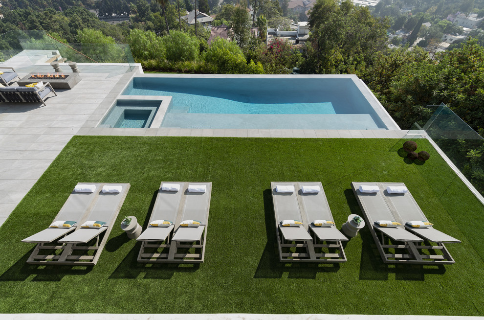 Exemple d'une très grande piscine à débordement et arrière moderne rectangle avec un bain bouillonnant et du carrelage.