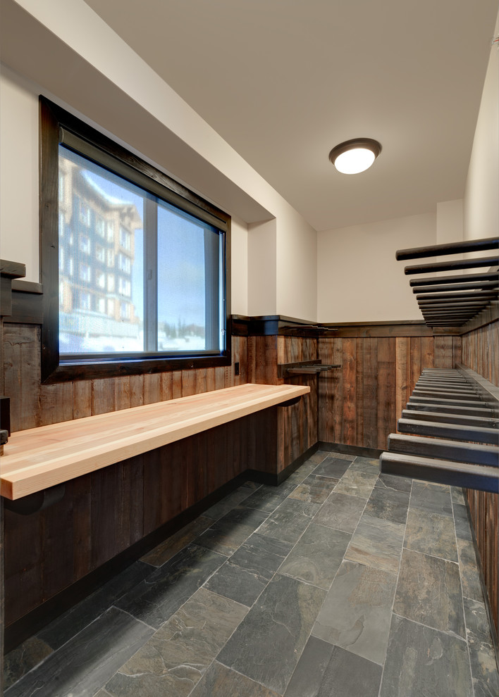 Inspiration for a large rustic slate floor and multicolored floor mudroom remodel with beige walls and a dark wood front door