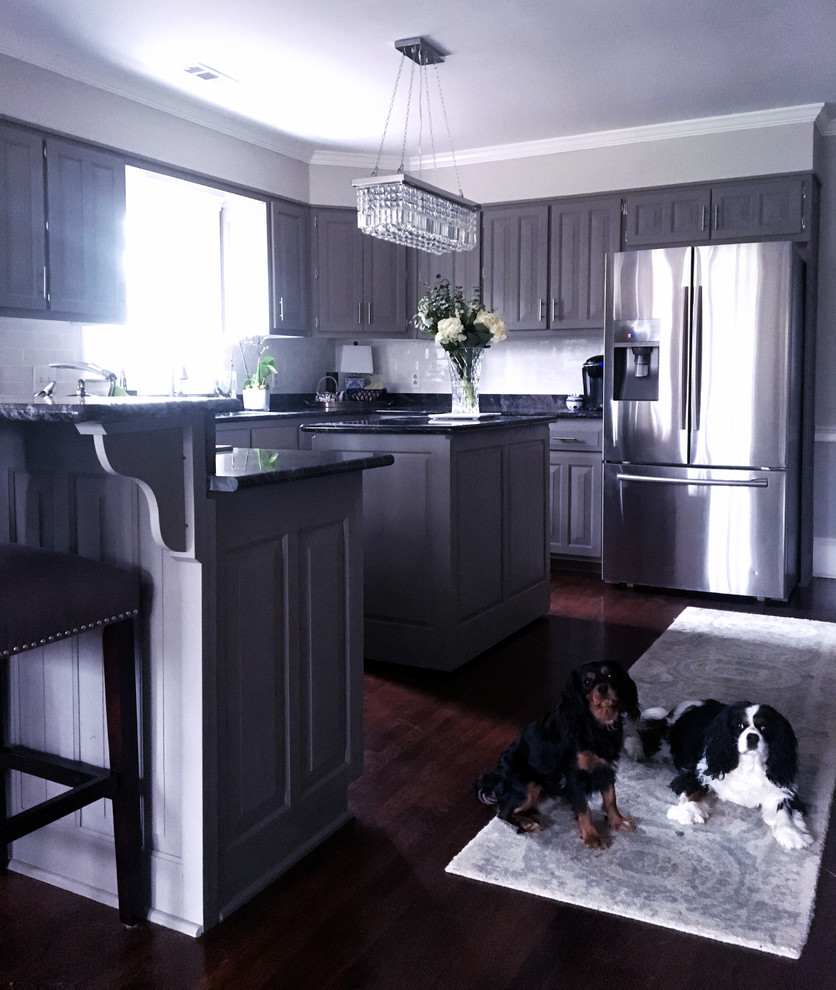 Inspiration for a mid-sized transitional l-shaped dark wood floor and brown floor enclosed kitchen remodel in Atlanta with an undermount sink, raised-panel cabinets, gray cabinets, quartzite countertops, white backsplash, subway tile backsplash, stainless steel appliances, an island and black countertops