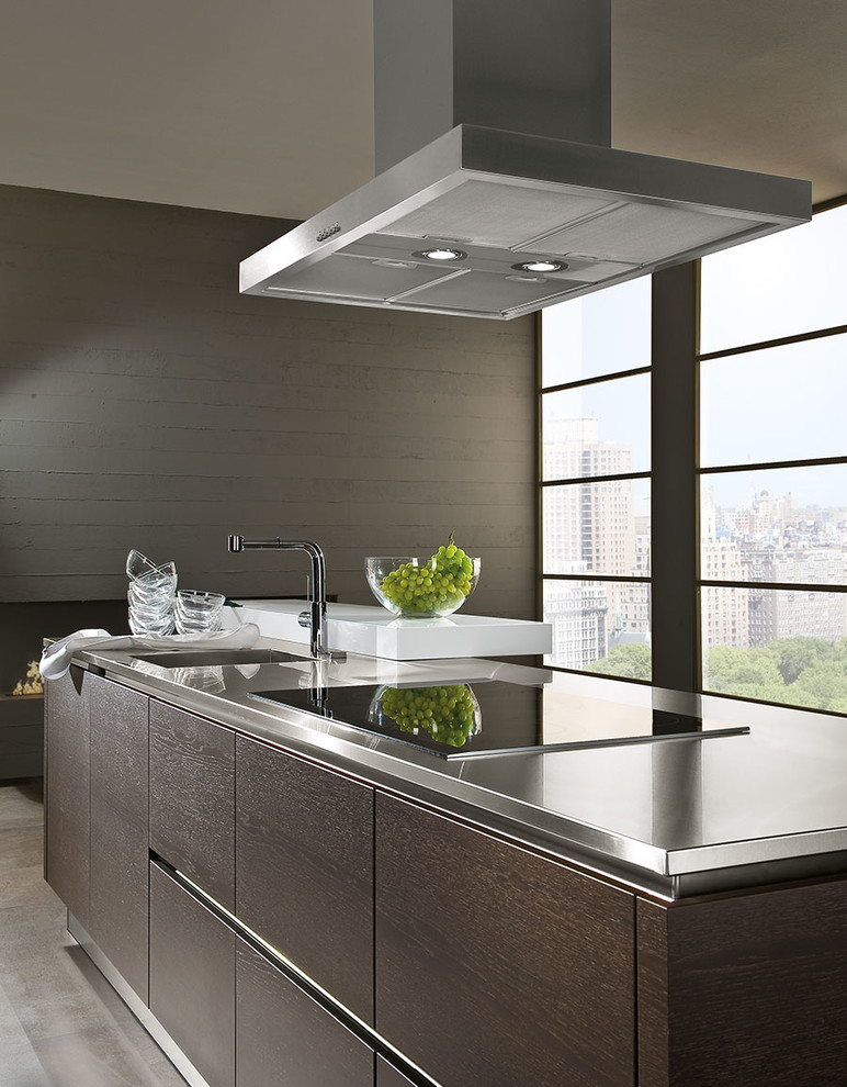 This is an example of a contemporary eat-in kitchen in London with an integrated sink, flat-panel cabinets, dark wood cabinets, stainless steel benchtops and with island.