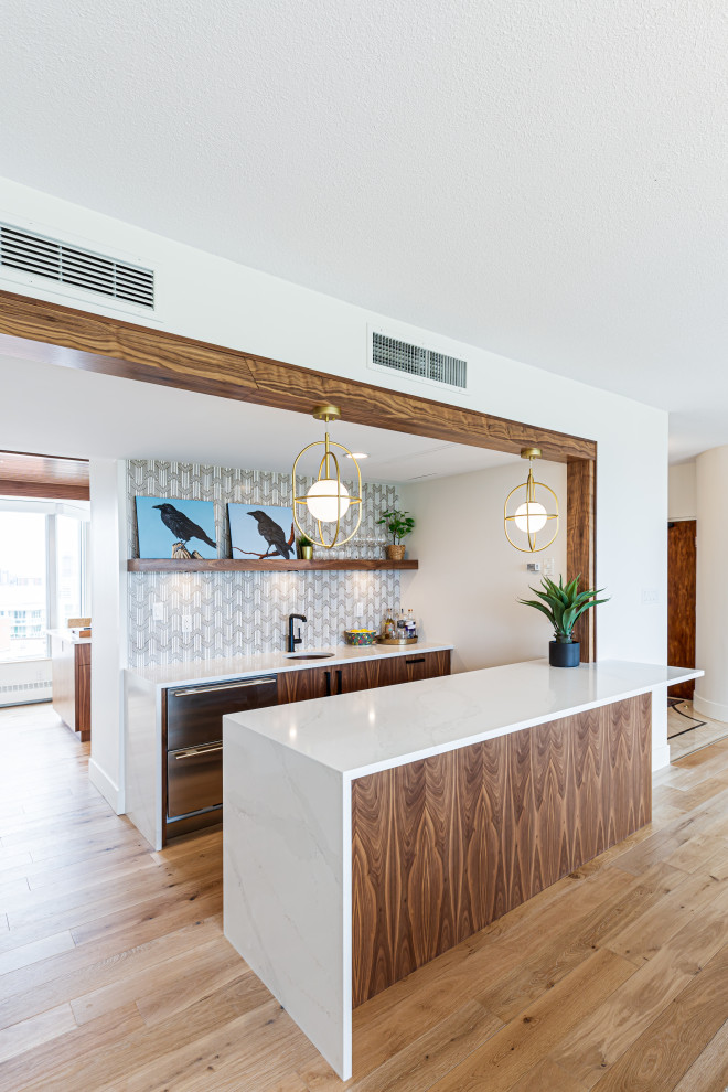 Example of a trendy galley light wood floor and brown floor wet bar design in Edmonton with an undermount sink, flat-panel cabinets, brown cabinets, quartzite countertops, white backsplash, ceramic backsplash and white countertops