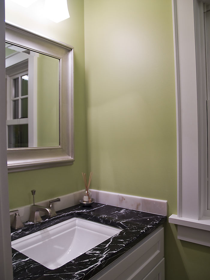 This is an example of a small contemporary powder room in Minneapolis with recessed-panel cabinets, white cabinets, green walls, an undermount sink, soapstone benchtops and multi-coloured benchtops.