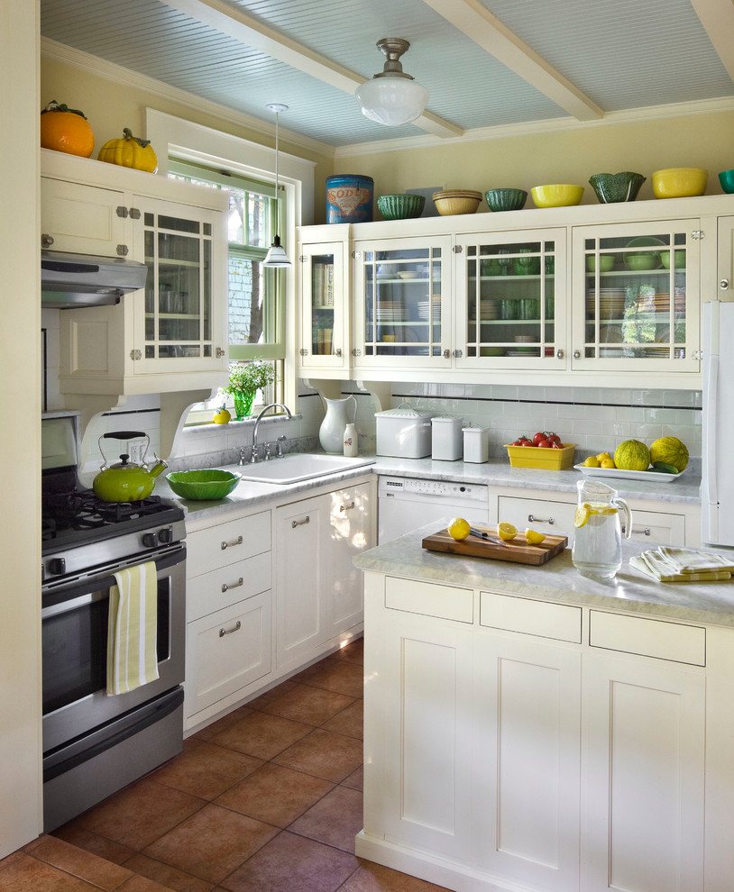 Kitchen - traditional l-shaped kitchen idea in New York with a drop-in sink, shaker cabinets, white cabinets, white backsplash, subway tile backsplash, stainless steel appliances and an island