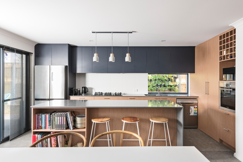 Design ideas for a mid-sized beach style l-shaped eat-in kitchen in Perth with an undermount sink, flat-panel cabinets, medium wood cabinets, white splashback, window splashback, stainless steel appliances, with island, grey floor and grey benchtop.