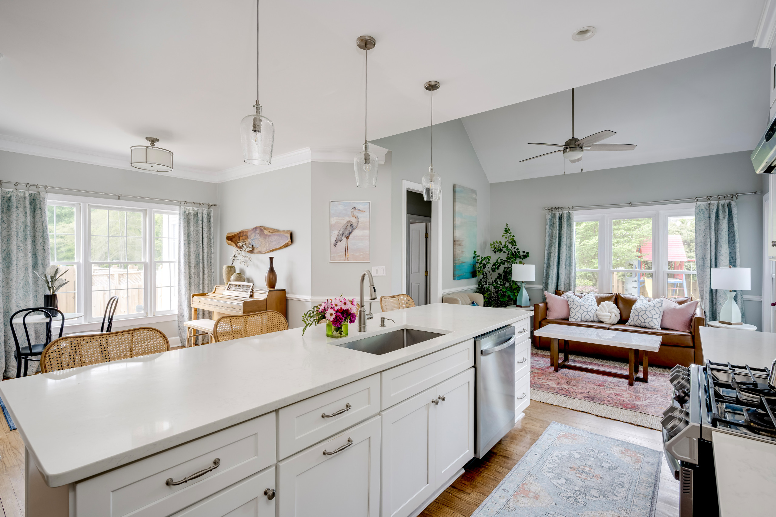 An open glance into this great room space that includes the kitchen, music room/breakfast area, and sitting room. The whites of the kitchen offset the colorful decor in the sitting room and music room