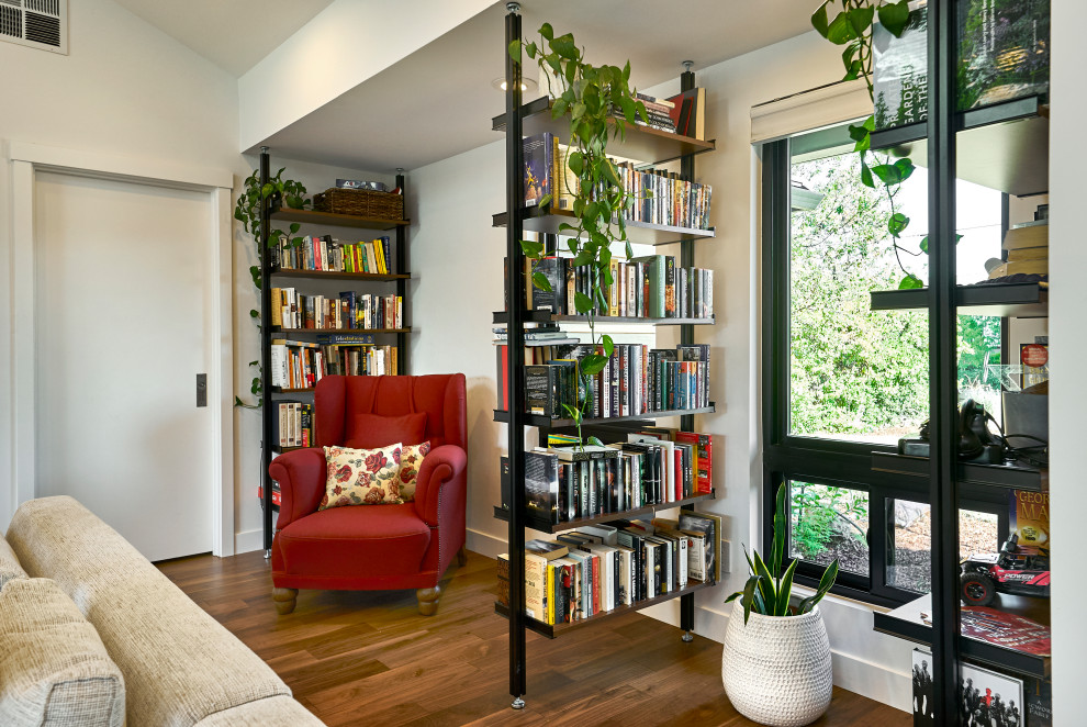 Immagine di un soggiorno minimalista di medie dimensioni e aperto con libreria, pareti bianche, pavimento in legno massello medio, pavimento marrone e pareti in legno