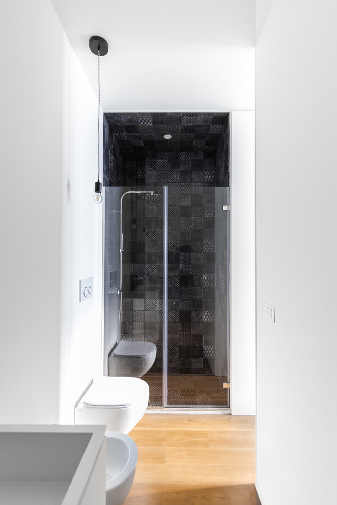 This is an example of a small contemporary bathroom in Milan with an alcove shower, a two-piece toilet, white walls and medium hardwood floors.