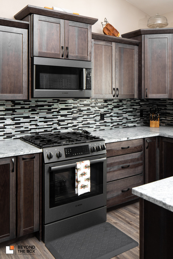 Example of a transitional u-shaped eat-in kitchen design with an undermount sink, shaker cabinets, dark wood cabinets, granite countertops, multicolored backsplash, black appliances, an island and gray countertops